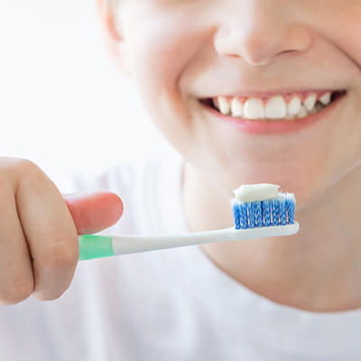 Junge hält eine Zahnbürste mit Zahnpasta in seiner Hand